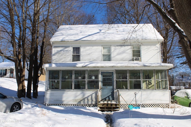 view of front facade with entry steps and a sunroom