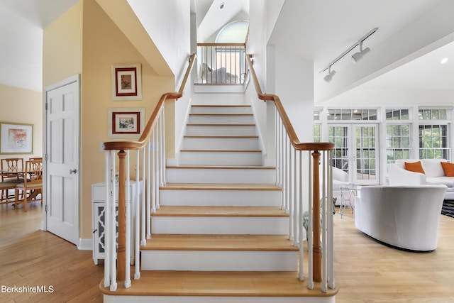 staircase with wood-type flooring and track lighting