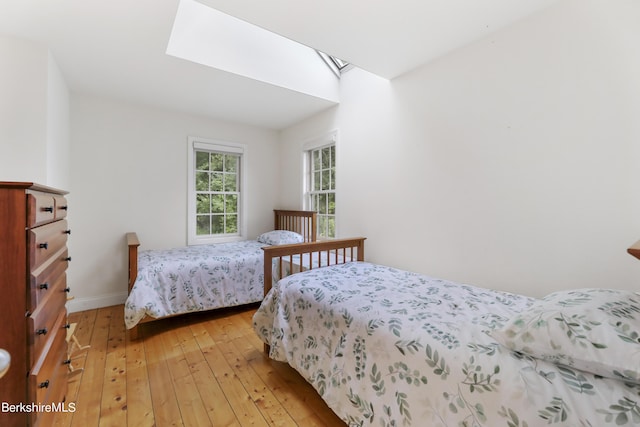 bedroom featuring light wood-type flooring and a skylight