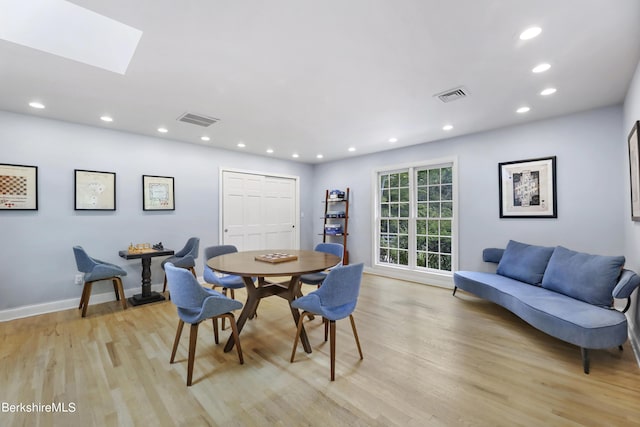 dining room with light hardwood / wood-style floors and a skylight