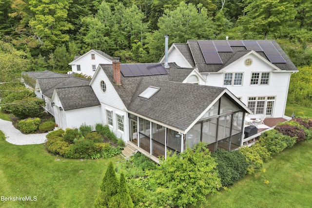 back of house with solar panels, a yard, and a sunroom