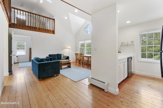 living room featuring vaulted ceiling, light wood-type flooring, and a baseboard heating unit