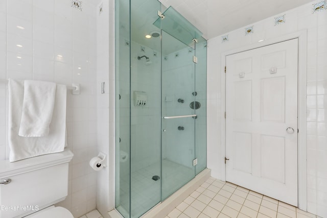 bathroom featuring tile patterned floors, a shower with door, and tile walls