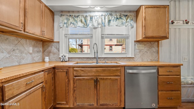 kitchen with wooden counters, backsplash, stainless steel dishwasher, brown cabinets, and a sink