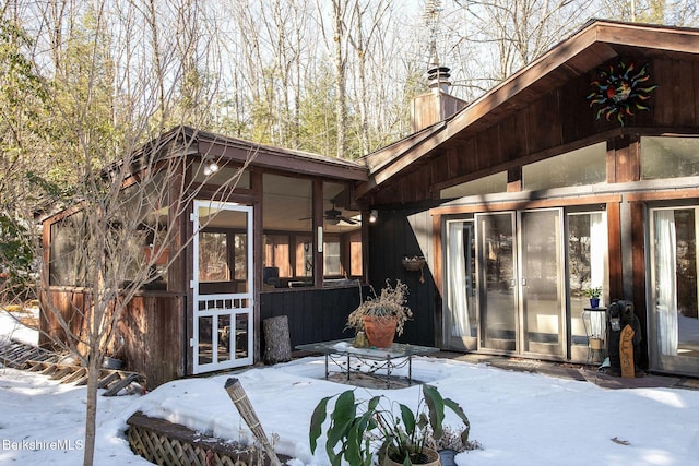 305 Shadow Ln, Sandisfield, MA 01255 - snow covered back of property featuring a sunroom, a chimney, and a ceiling fan