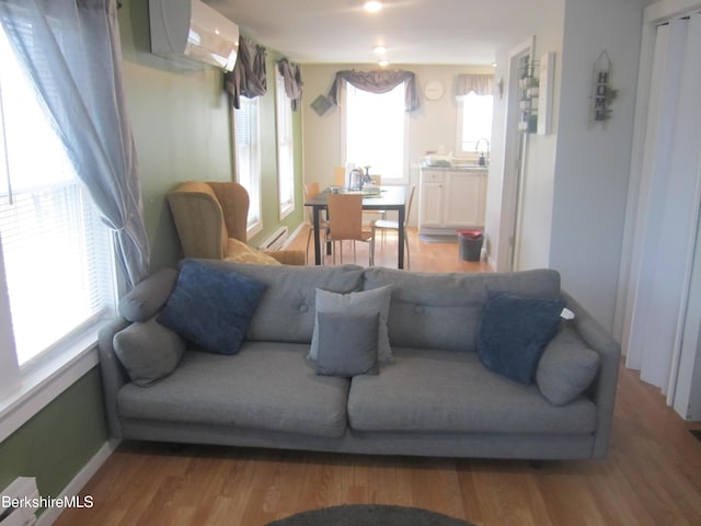 living room with a wall mounted air conditioner and hardwood / wood-style flooring