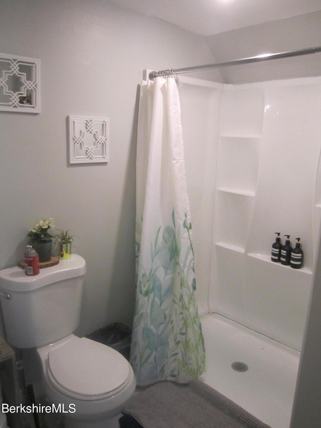 bathroom featuring toilet and curtained shower