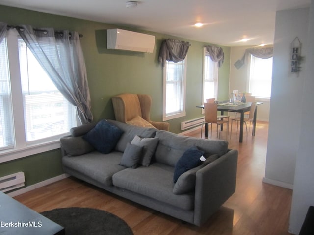 living room featuring an AC wall unit, hardwood / wood-style floors, and baseboard heating