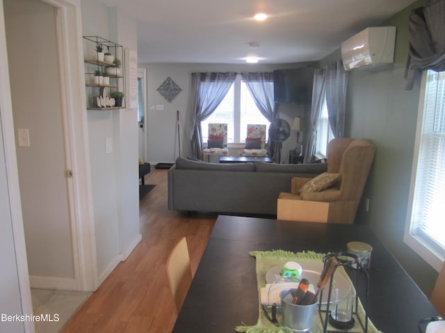 living room with a wealth of natural light, hardwood / wood-style floors, and a wall mounted air conditioner