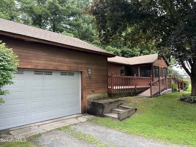 view of front of home with a garage, a front lawn, and a wooden deck