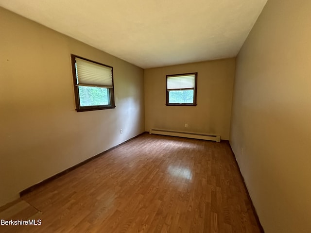 empty room with wood-type flooring and a baseboard heating unit