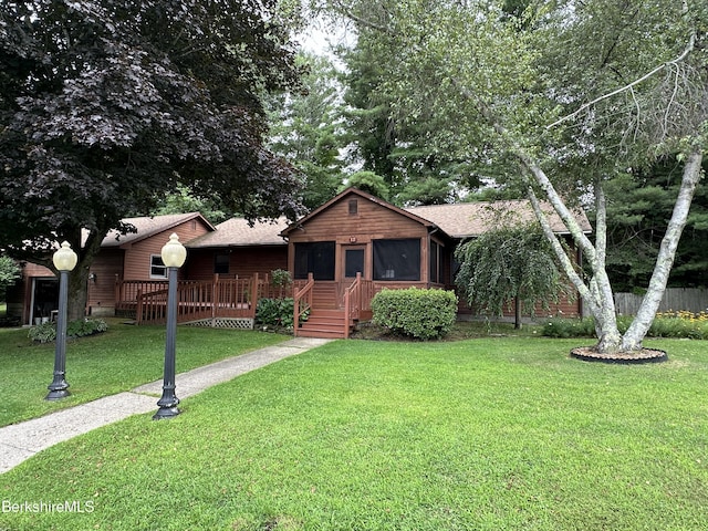 view of front of property featuring a sunroom, a wooden deck, and a front yard