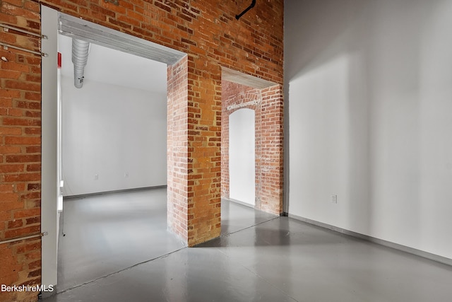 spare room featuring concrete floors and brick wall