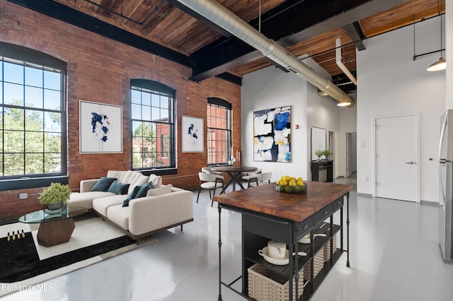 living room featuring wood ceiling, concrete flooring, brick wall, beamed ceiling, and a high ceiling