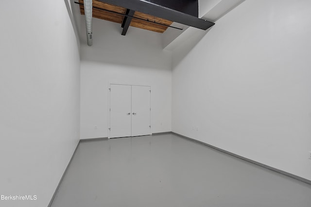 spare room with beam ceiling and concrete flooring