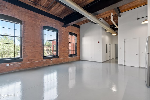 interior space with plenty of natural light, beamed ceiling, and brick wall