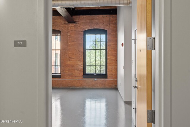 interior space featuring beamed ceiling and brick wall