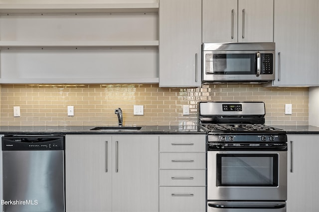 kitchen with tasteful backsplash, sink, dark stone counters, and appliances with stainless steel finishes