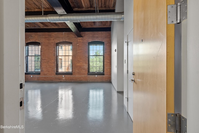 unfurnished room featuring wooden ceiling, beamed ceiling, and brick wall