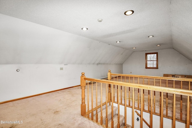 bonus room featuring carpet flooring, vaulted ceiling, a textured ceiling, and baseboards