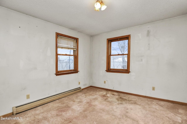 empty room with a baseboard heating unit, a textured ceiling, baseboards, and light colored carpet