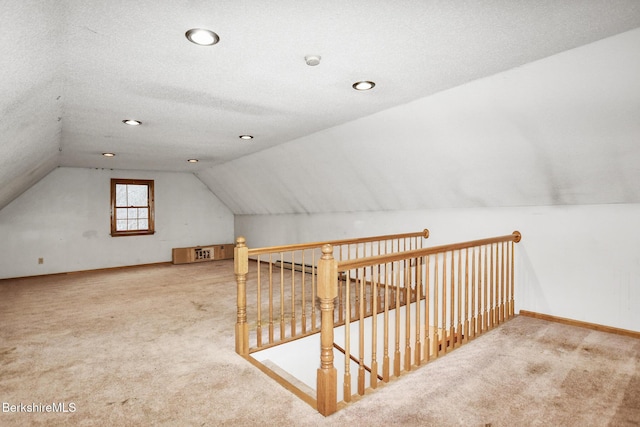 additional living space with carpet, vaulted ceiling, a textured ceiling, and baseboards