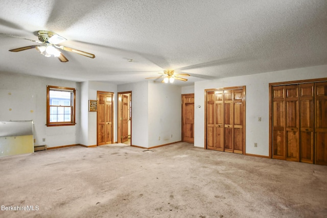 spare room featuring a baseboard heating unit, a textured ceiling, baseboards, and light colored carpet