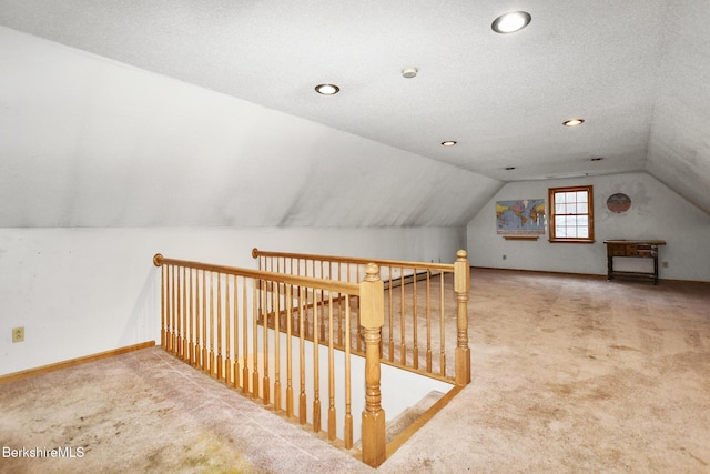 bonus room featuring lofted ceiling, carpet, baseboards, and a textured ceiling