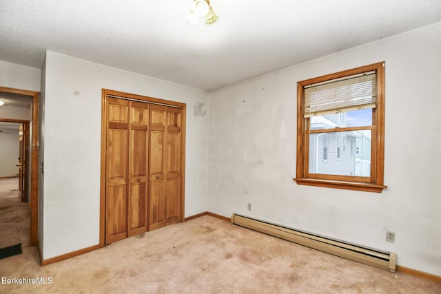 unfurnished bedroom with light carpet, a baseboard radiator, baseboards, and a closet