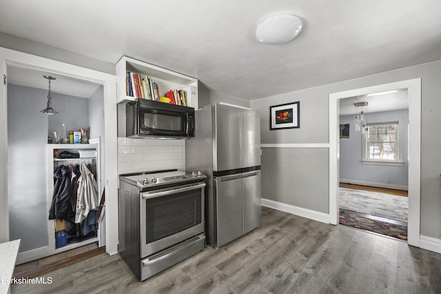 kitchen with wood-type flooring, backsplash, stainless steel appliances, and pendant lighting