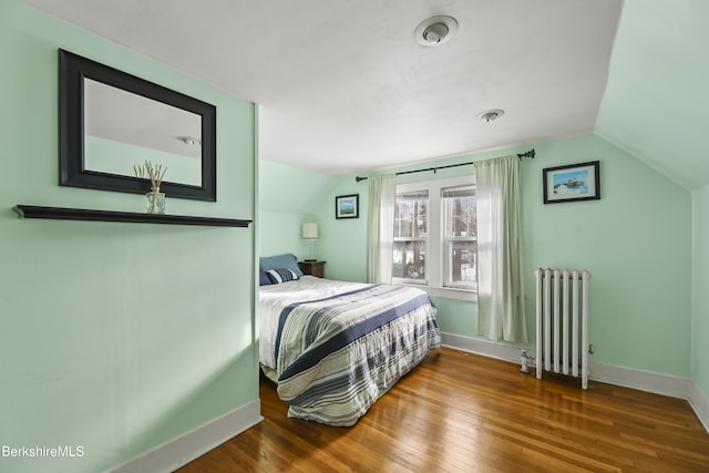 bedroom with radiator, lofted ceiling, and hardwood / wood-style flooring