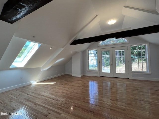 additional living space featuring lofted ceiling with skylight, french doors, and hardwood / wood-style flooring