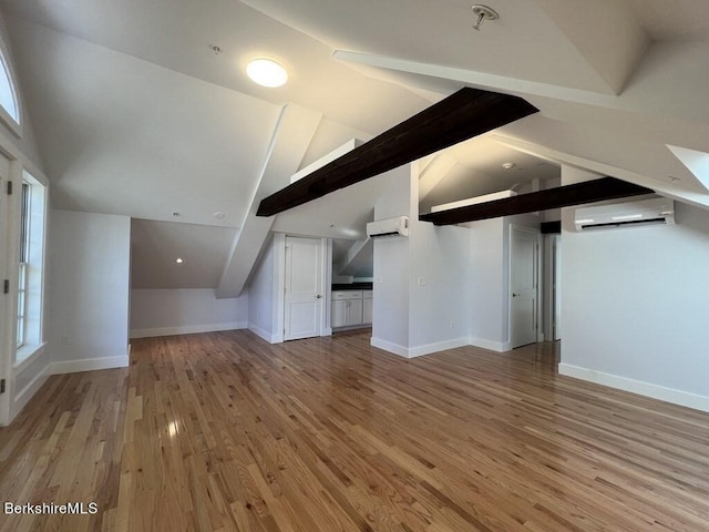 additional living space featuring lofted ceiling with beams, a wall mounted air conditioner, and hardwood / wood-style flooring