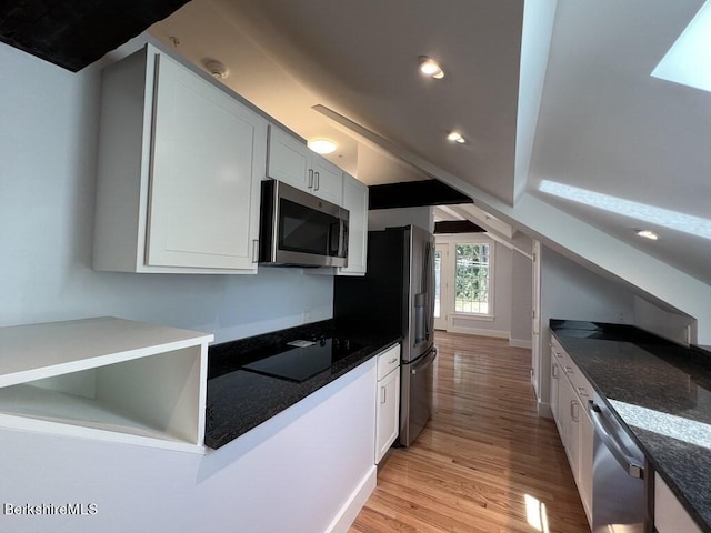 kitchen with white cabinets, dark stone countertops, light wood-type flooring, and stainless steel appliances