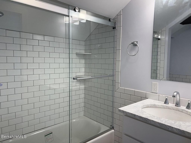 bathroom with combined bath / shower with glass door, vanity, and tile walls