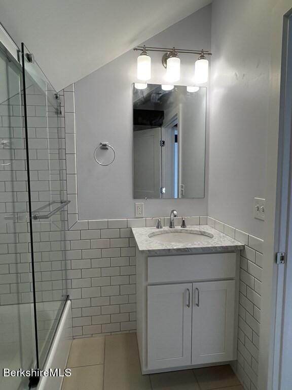 bathroom featuring vanity, vaulted ceiling, tile patterned floors, and enclosed tub / shower combo