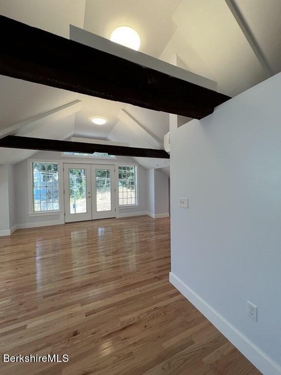 unfurnished living room with vaulted ceiling with beams, hardwood / wood-style floors, and french doors