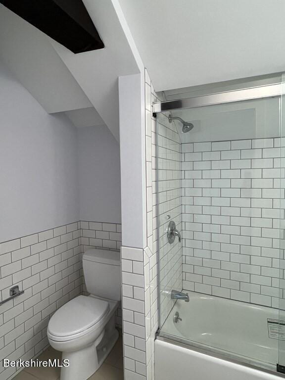 bathroom featuring tile patterned flooring, toilet, enclosed tub / shower combo, and tile walls