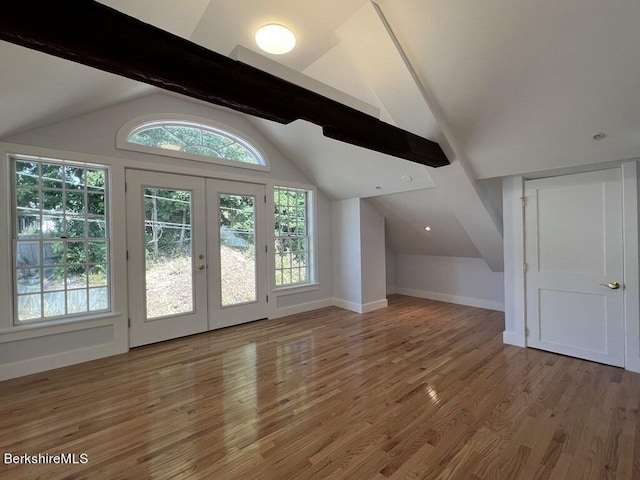 additional living space featuring vaulted ceiling with beams, wood-type flooring, a wealth of natural light, and french doors