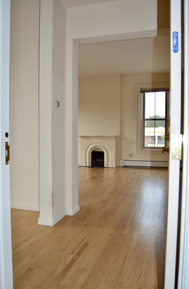 36 Holden St Unit A, North Adams, MA 01247 - unfurnished living room featuring a baseboard radiator, light wood-style floors, and a fireplace
