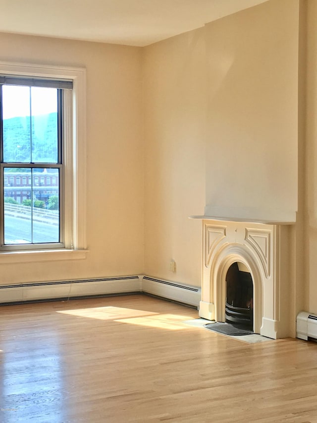 36 Holden St Unit A, North Adams, MA 01247 - unfurnished living room featuring light wood-style flooring, a fireplace with flush hearth, and a baseboard radiator