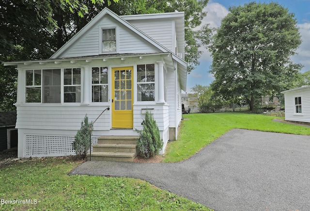 view of front of home with a sunroom and a front yard