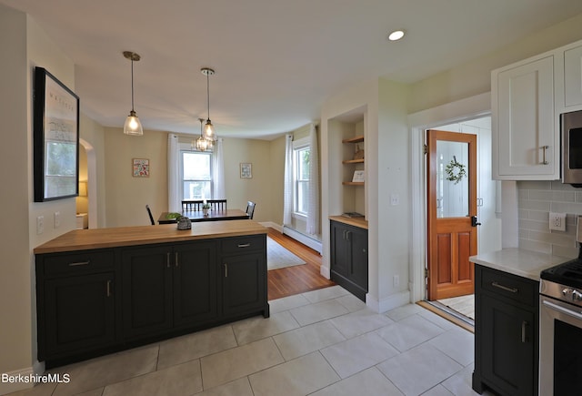 kitchen with decorative backsplash, appliances with stainless steel finishes, baseboard heating, light tile patterned floors, and pendant lighting