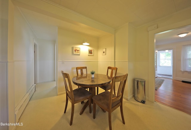 carpeted dining area with ornamental molding and a baseboard heating unit