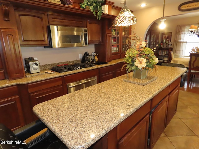 94 Gale Ave, Pittsfield, MA 01201 - kitchen featuring stainless steel microwave, black gas stovetop, arched walkways, light stone counters, and light tile patterned floors