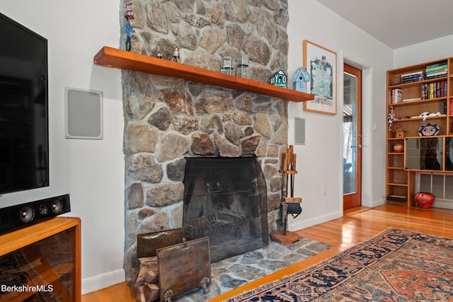 living area with baseboards, wood finished floors, and a fireplace