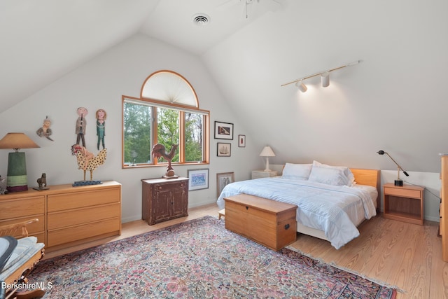 bedroom featuring vaulted ceiling, rail lighting, light wood-style flooring, and visible vents