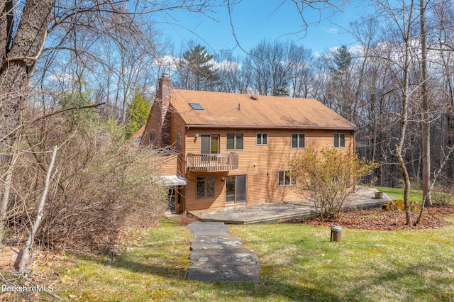 back of property with a lawn, a chimney, a balcony, and a patio area