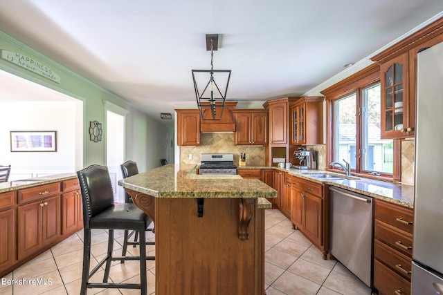 kitchen with stainless steel appliances, sink, hanging light fixtures, a breakfast bar area, and light tile patterned flooring