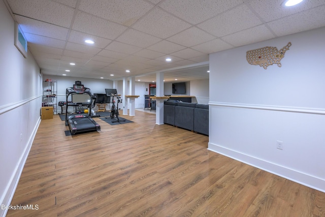 exercise area featuring wood-type flooring and a drop ceiling